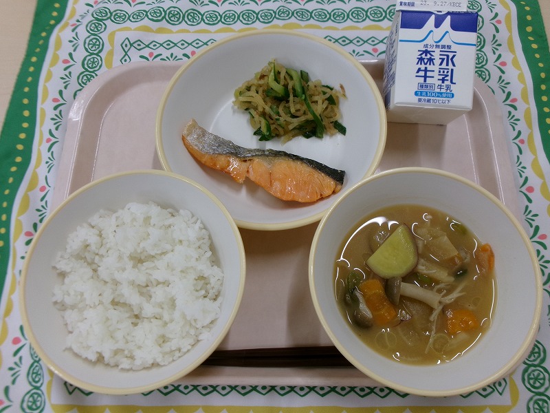ピンクのトレーに給食が右上から反時計回りで牛乳、鮭の塩焼き、野菜のおかか和え、ご飯、秋の具だくさん味噌汁と並んでいる写真