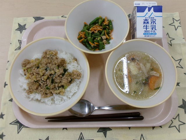 ピンクのトレーに給食が右上から反時計回りで牛乳、いんげんのツナ炒め、肉みそごはん、きのこの和風スープと並んでいる写真