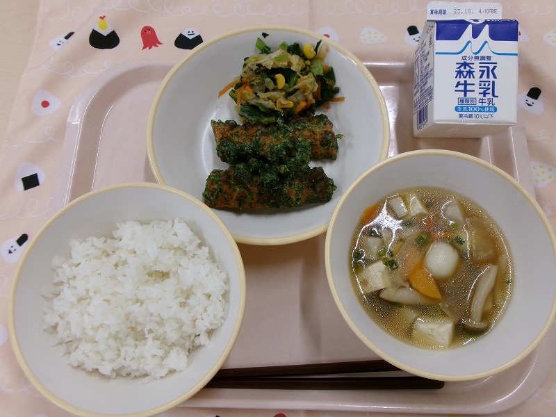 ピンクのトレーに給食が右上から反時計回りで牛乳、ちくわの磯辺揚げとカラフルおひたし、ご飯、月見汁と並んでいる写真