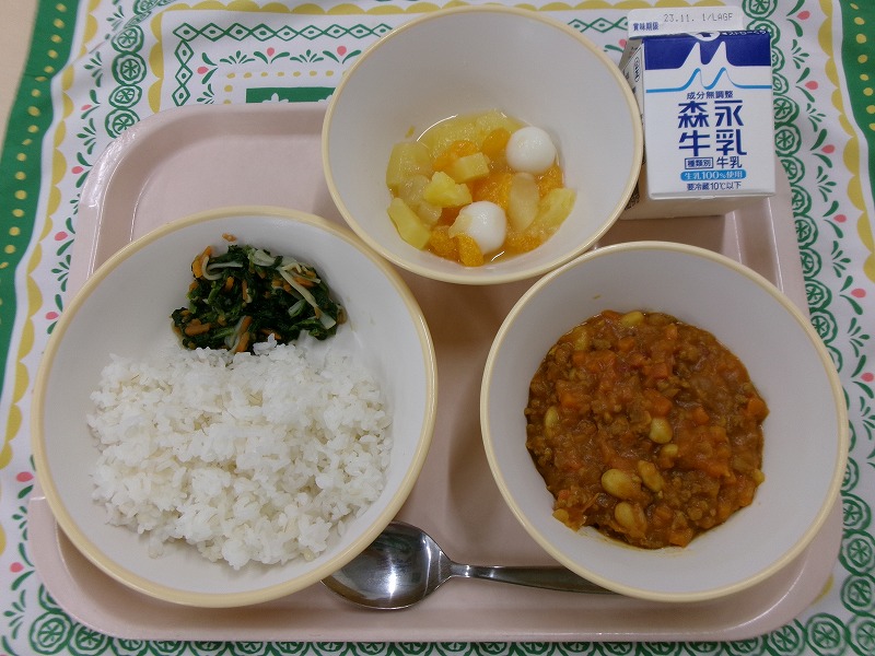 ピンクのトレーに給食が右上から反時計回りで牛乳、白玉フルーツポンチ、（もち麦入りごはん）とほうれんそうソテー、豆キーマカレーと並んでいる写真