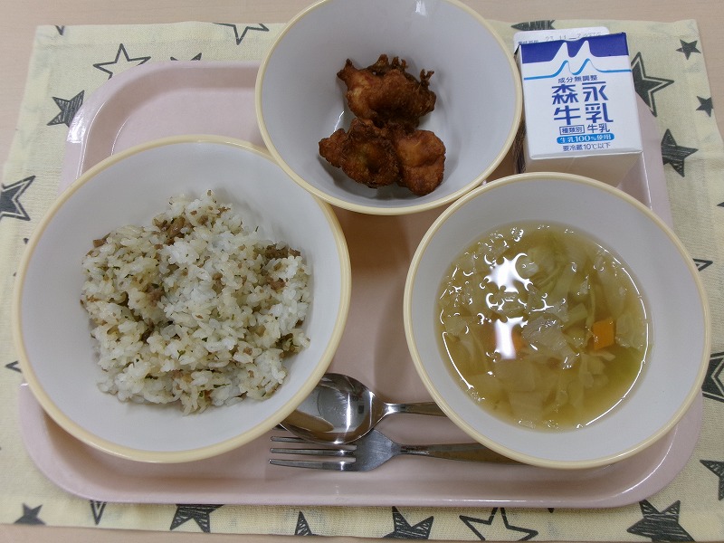 ピンクのトレーに給食が右上から反時計回りで牛乳、鶏肉のフリッター、ごぼうピラフ、野菜スープと並んでいる写真