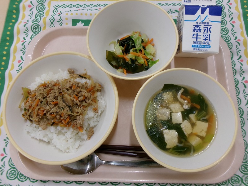 ピンクのトレーに給食が右上から反時計回りで牛乳、わかめサラダ、ビビンバ丼、五目スープと並んでいる写真