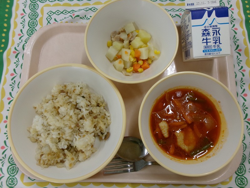 ピンクのトレーに給食が右上から反時計回りで牛乳、じゃがいものソテー、ご飯、鶏肉のトマト煮と並んでいる写真