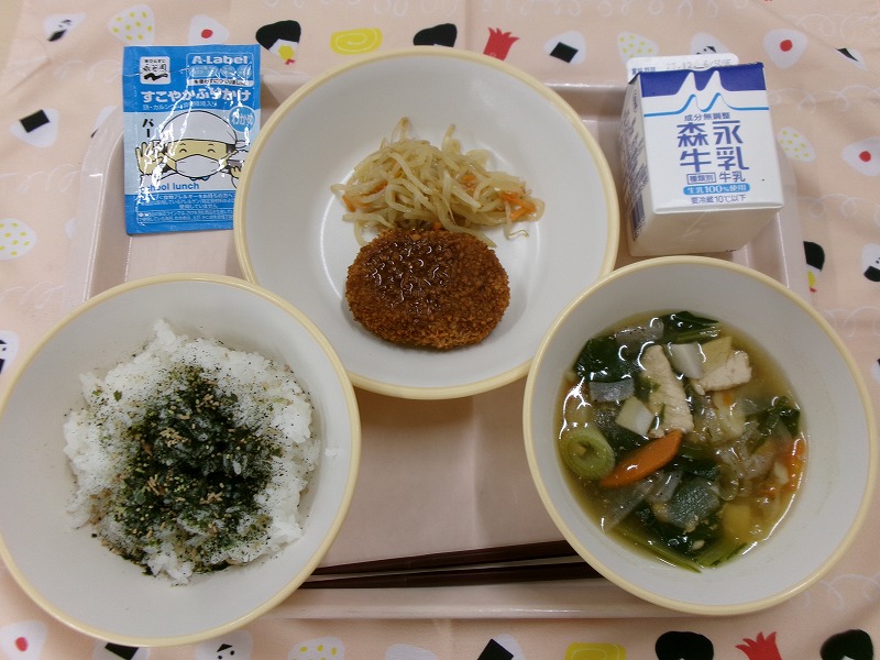 ピンクのトレーに給食が右上から反時計回りで牛乳、メンチカツとピリ辛もやし、ご飯（わかめふりかけ）、のっぺい汁と並んでいる写真