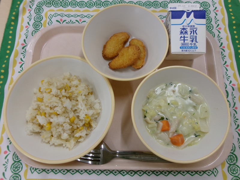 ピンクのトレーに給食が右上から反時計回りで牛乳、チキンナゲット、コーンピラフ、白菜シチューと並んでいる写真