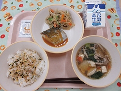ピンクのトレーに給食が右上から反時計回りで牛乳、サバの味噌煮、さらだ、ふりかけごはん、吸い物と並んでいる写真