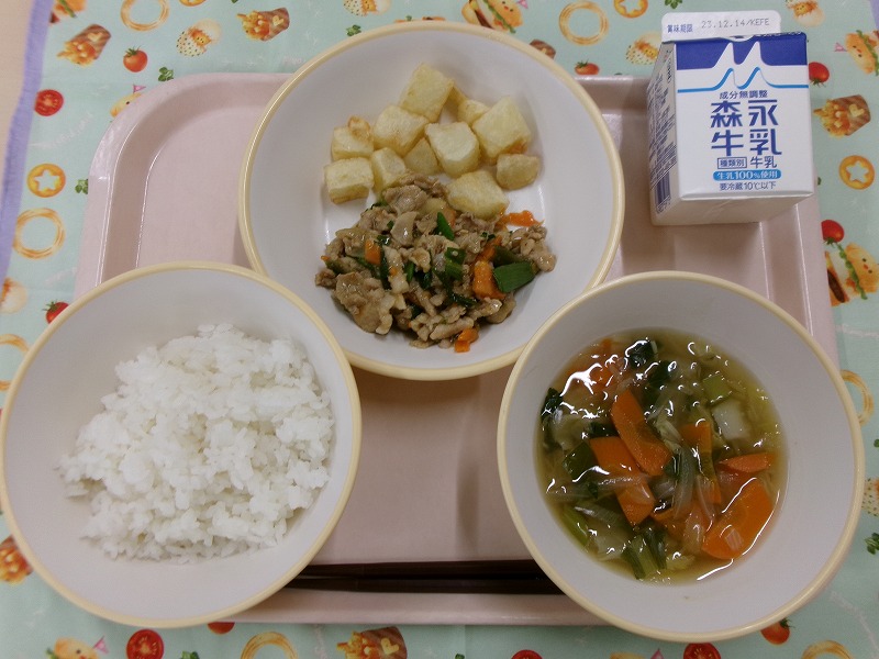 ピンクのトレーに給食が右上から反時計回りで牛乳、葉にんにくと豚肉のピリ辛炒め、あげいも、ご飯、白菜のとろみ汁と並んでいる写真