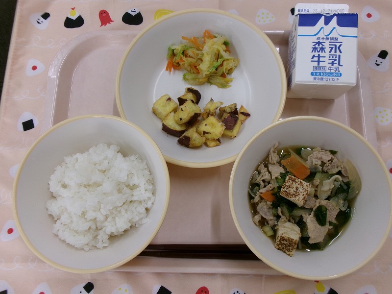 ピンクのトレーに給食が右上から反時計回りで牛乳、さつまいものコロコロ揚げと白菜漬けすき焼き風煮、ご飯、すき焼き風煮と並んでいる写真