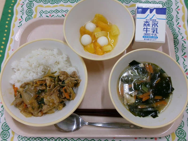 ピンクのトレーに給食が右上から反時計回りで牛乳、白玉フルーツポンチ、豚キムチごはん、韓国風わかめスープと並んでいる写真