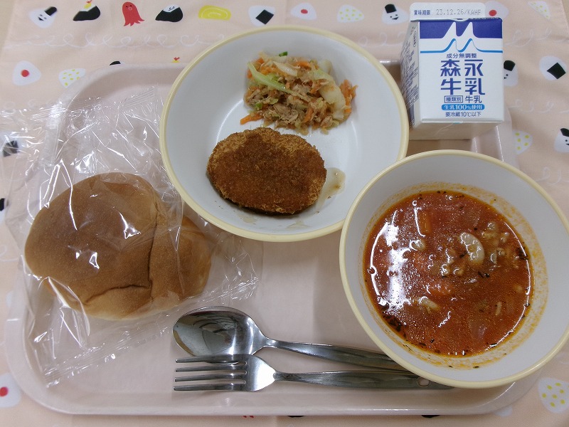 ピンクのトレーに給食が右上から反時計回りで牛乳、コロッケとツナサラダトマトスープ、ロールパン、トマトスープと並んでいる写真