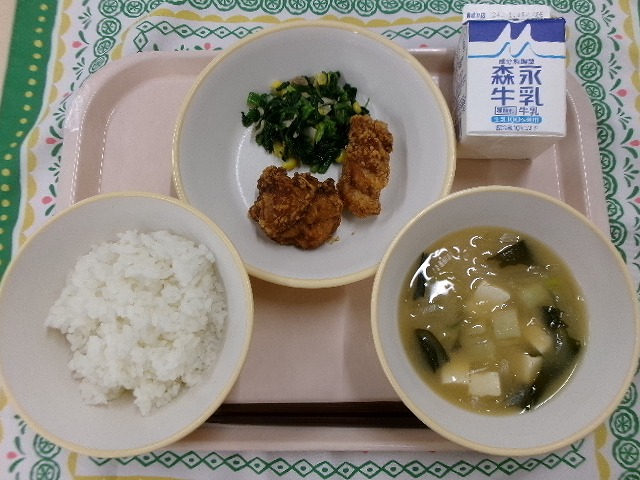 ピンクのトレーに給食が右上から反時計回りで牛乳、鶏の竜田揚げとポパイサラダ、ご飯、じゃがいもの味噌汁と並んでいる写真