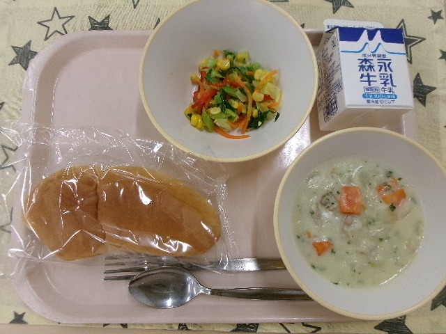 ピンクのトレーに給食が右上から反時計回りで牛乳、カラフルサラダ、ソフトフランスパン、チキンのクリームシチューと並んでいる写真