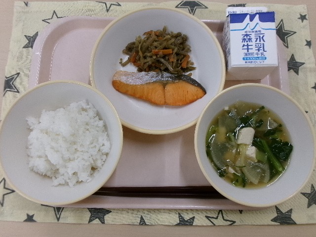 ピンクのトレーに給食が右上から反時計回りで牛乳、鮭の塩焼きときんぴらごぼう、ご飯、豆腐と大根のとろみ汁と並んでいる写真