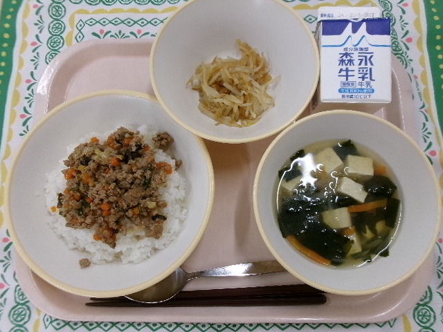 ピンクのトレーに給食が右上から反時計回りで牛乳、ナムル、ビビンバ丼、わかめスープと並んでいる写真