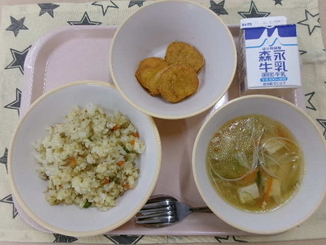ピンクのトレーに給食が右上から反時計回りで牛乳、チキンナゲット、カレーピラフ、ビーフンスープと並んでいる写真