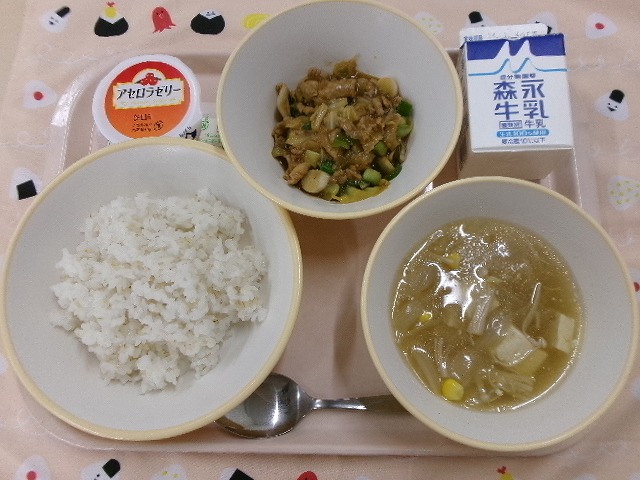 ピンクのトレーに給食が右上から反時計回りで牛乳、ホイコーロー、アセロラゼリー、もち麦入りごはん、コーン中華スープと並んでいる写真