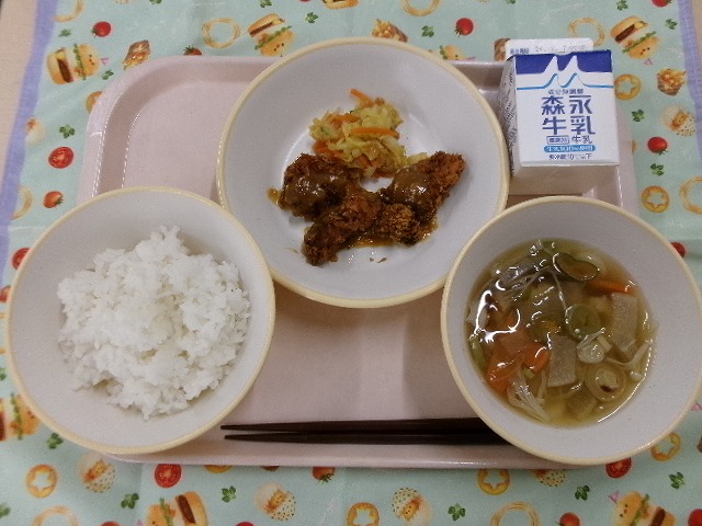 ピンクのトレーに給食が右上から反時計回りで牛乳、みそカツと白菜漬け、ご飯、のっぺい汁と並んでいる写真