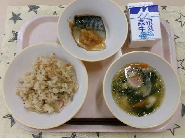 ピンクのトレーに給食が右上から反時計回りで牛乳、鯖のみぞれ煮風、かやくごはん、白玉汁と並んでいる写真