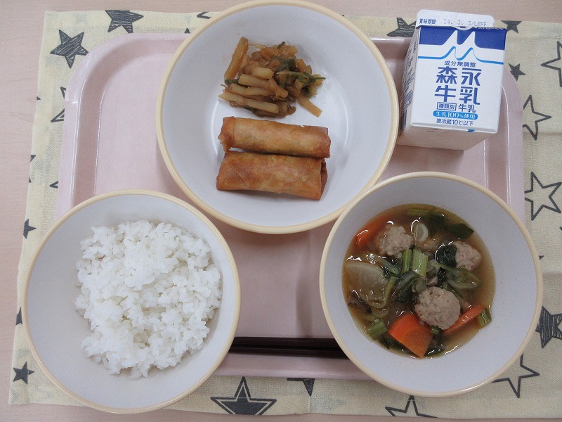 ピンクのトレーに給食が右上から反時計回りで牛乳、春巻きとじゃがいものオイスターソース炒め、ご飯、肉だんごスープと並んでいる写真