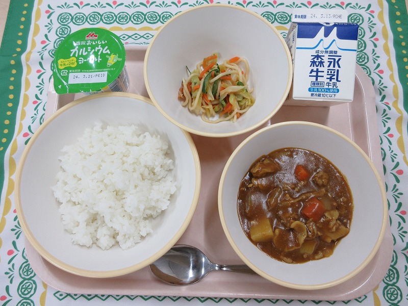 ピンクのトレーに給食が右上から反時計回りで牛乳、玉ねぎドレッシングサラダ、ヨーグルト、ご飯、カレーと並んでいる写真