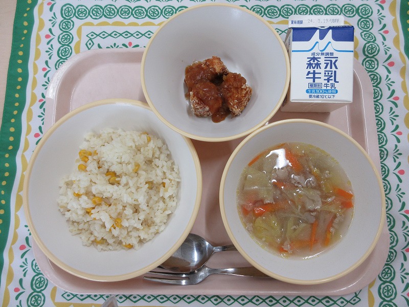 ピンクのトレーに給食が右上から反時計回りで牛乳、めかじきのバーベキューソース、コーンピラフ、スコッチブロスと並んでいる写真