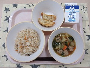 ピンクのトレーに給食が右上から反時計回りで牛乳、揚げ餃子、鶏五目ごはん、根菜と肉だんごの煮物と並んでいる写真
