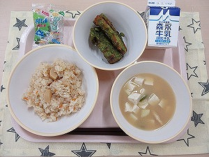 ピンクのトレーに給食が右上から反時計回りで牛乳、ちくわの新茶揚げ、ミニ柏餅、たけのこごはん、豆腐の味噌汁と並んでいる写真