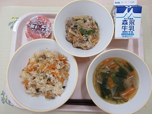 ピンクのトレーに給食が右上から反時計回りで牛乳、チンジャオロース、ココアムース、中華風おこわ、肉団子スープと並んでいる写真