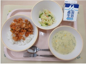 ピンクのトレーに給食が右上から反時計回りで牛乳、ミックスサラダ、チキンライス、コーンシチューと並んでいる写真