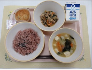 ピンクのトレーに給食が右上から反時計回りで牛乳、肉野菜炒め、秦野の桜カップケーキ、赤飯（ごま塩）、かぶの味噌汁と並んでいる写真