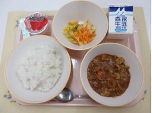 ピンクのトレーに給食が右上から反時計回りで牛乳、コーンソテー、いちごゼリー、ご飯、カレーと並んでいる写真