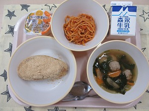 ピンクのトレーに給食が右上から反時計回りで牛乳、スパゲティミートソース、フルーツ野菜ゼリー、きな粉揚げパン 、肉団子スープと並んでいる写真