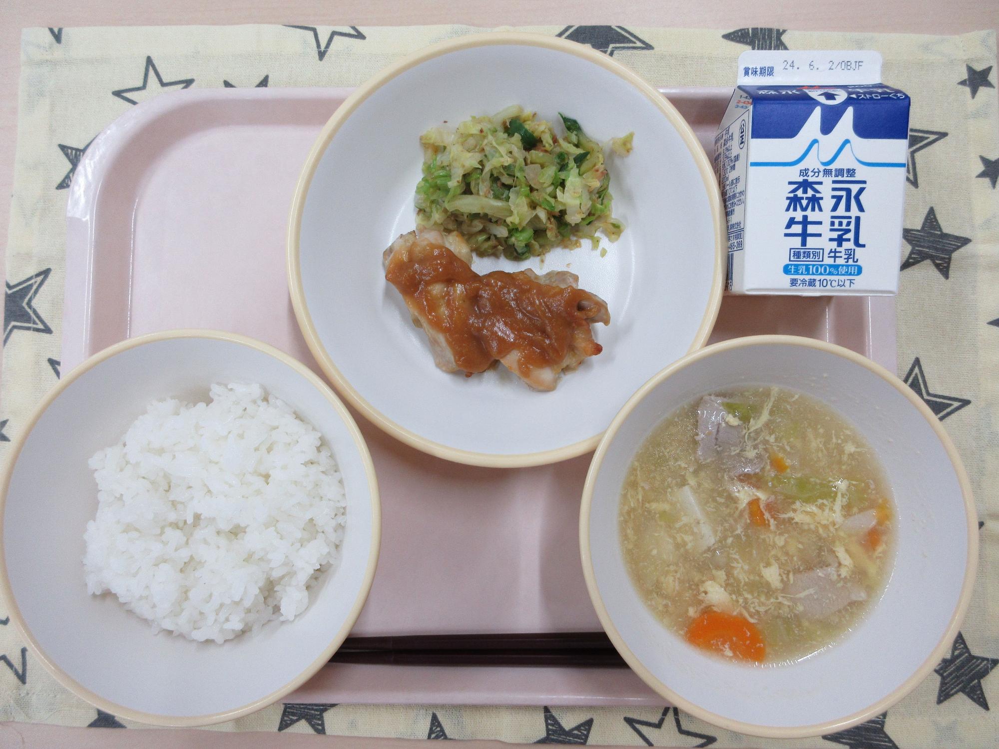 ピンクのトレーに給食が右上から反時計回りで牛乳、鶏肉の味噌焼きとキャベツのおかか和え、ご飯、卵スープと並んでいる写真