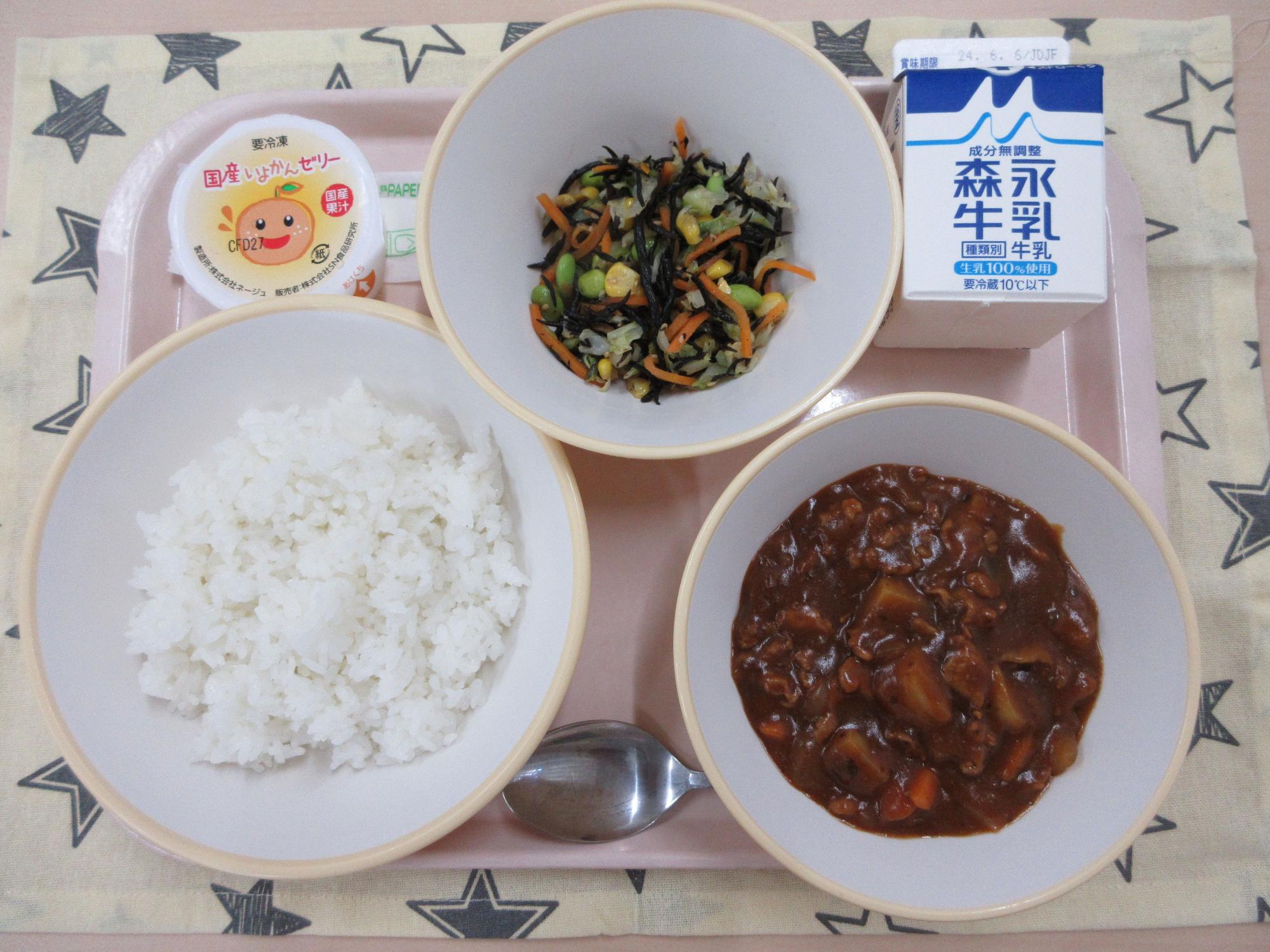 ピンクのトレーに給食が右上から反時計回りで牛乳、ひじきのサラダ 、いよかんゼリー、ご飯、ハヤシライスと並んでいる写真