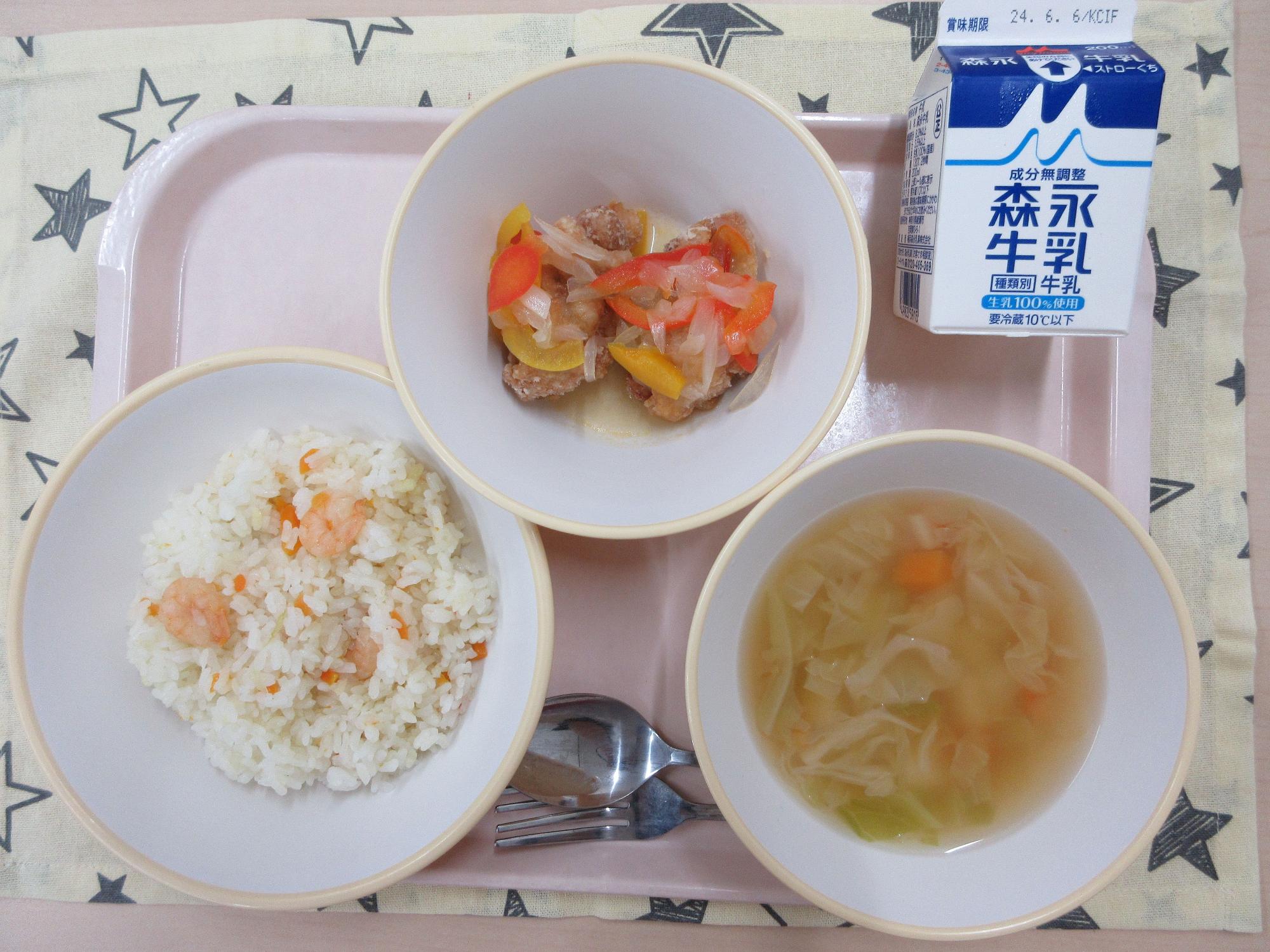 ピンクのトレーに給食が右上から反時計回りで牛乳、鶏肉のマリネ、えびピラフ、ABCスープと並んでいる写真