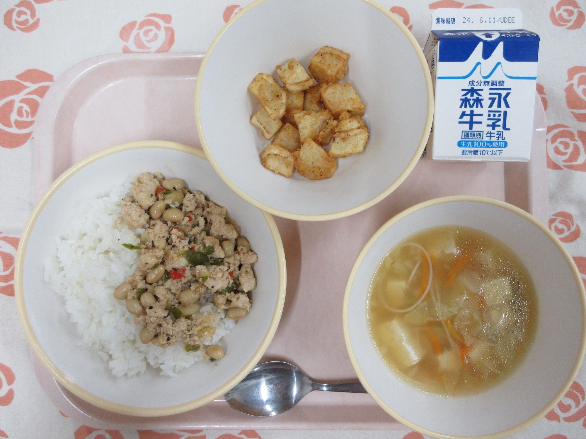 ピンクのトレーに給食が右上から反時計回りで牛乳、スパイシーポテト、ガパオライス、ビーフンスープと並んでいる写真