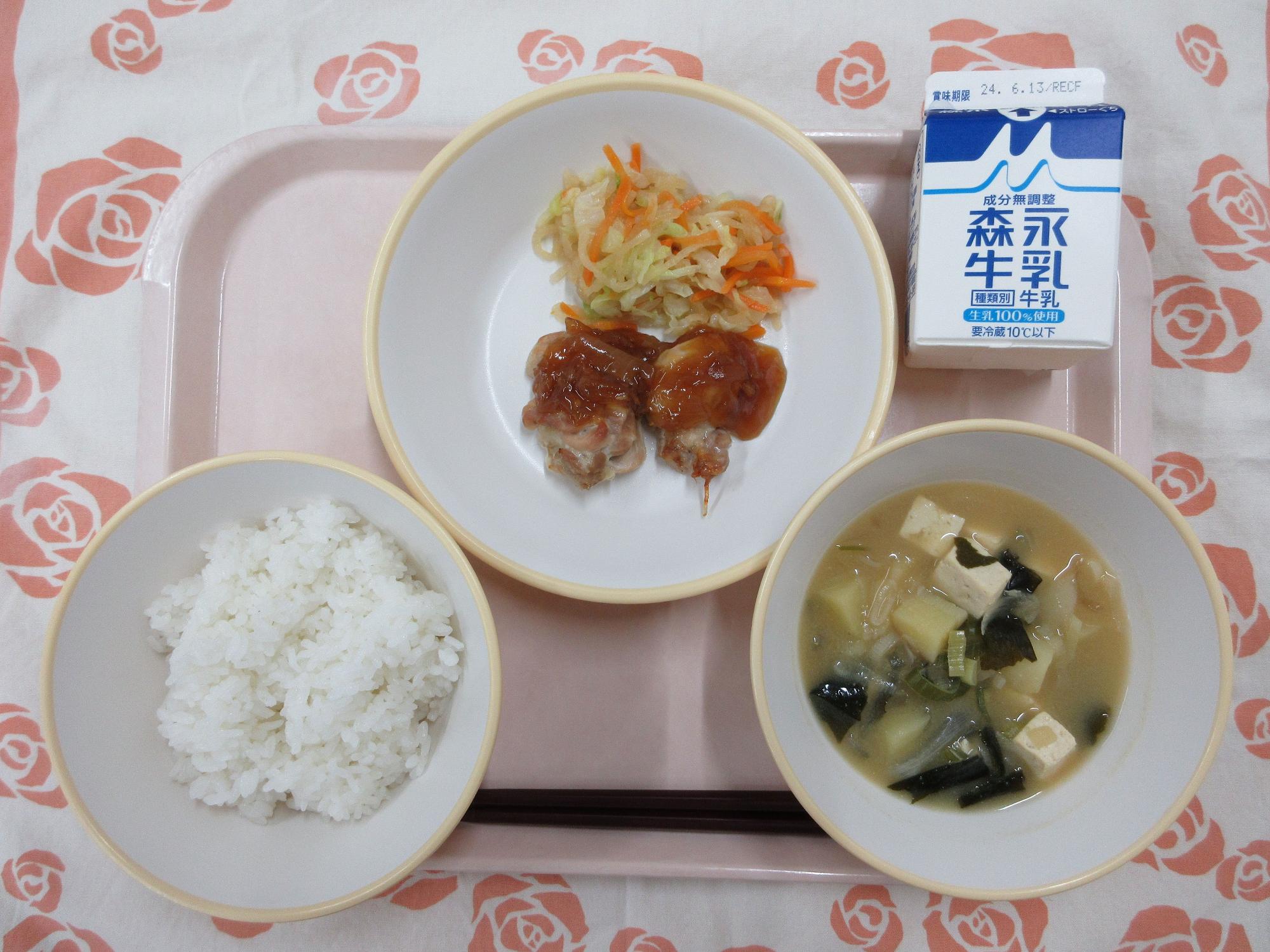 ピンクのトレーに給食が右上から反時計回りで牛乳、鶏肉の生姜焼きとじゃこサラダ、ご飯、じゃがいもの味噌汁と並んでいる写真