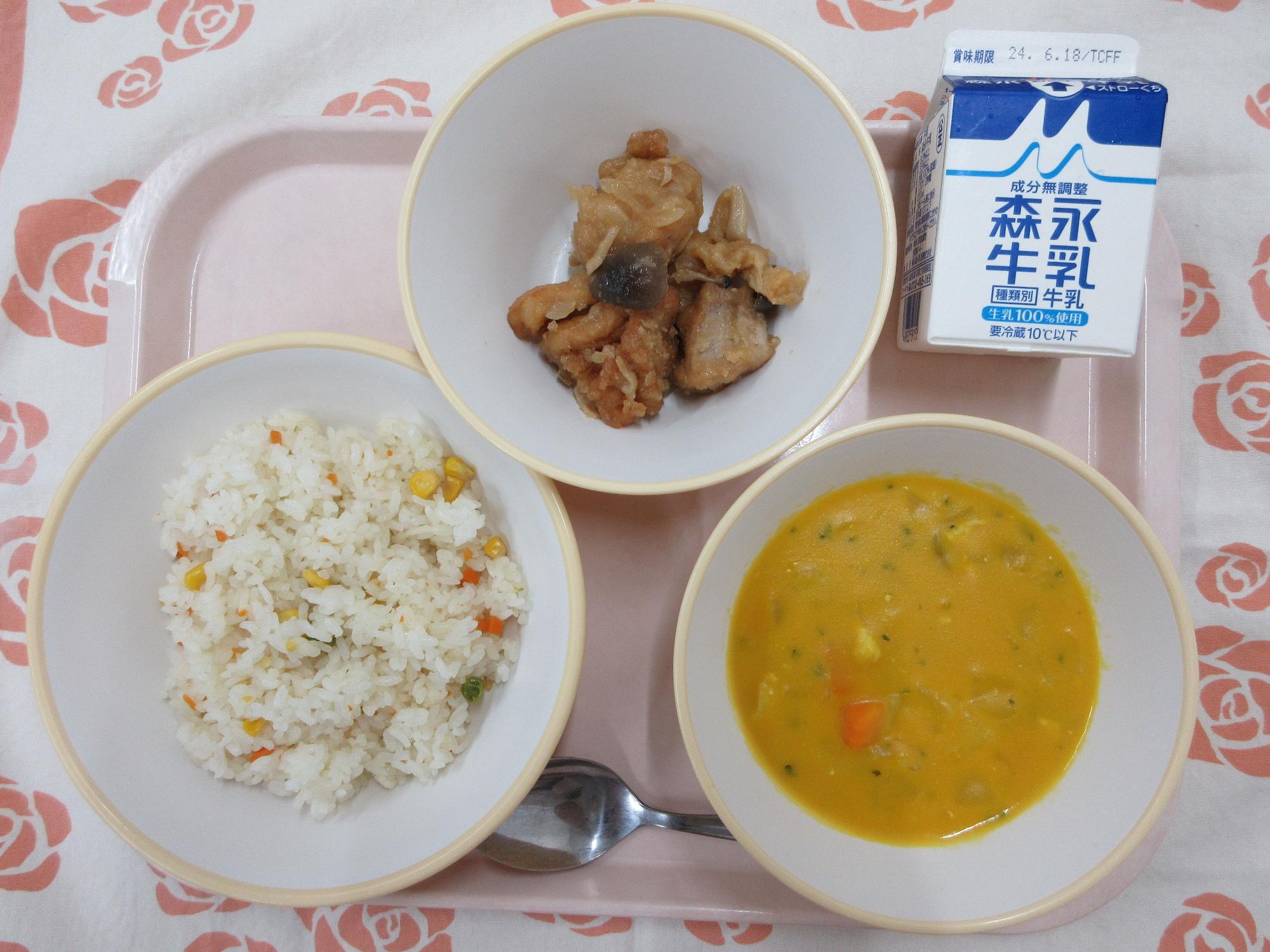 ピンクのトレーに給食が右上から反時計回りで牛乳、鶏肉のガーリック炒め、ベジピラフ、かぼちゃのクリームスープ と並んでいる写真