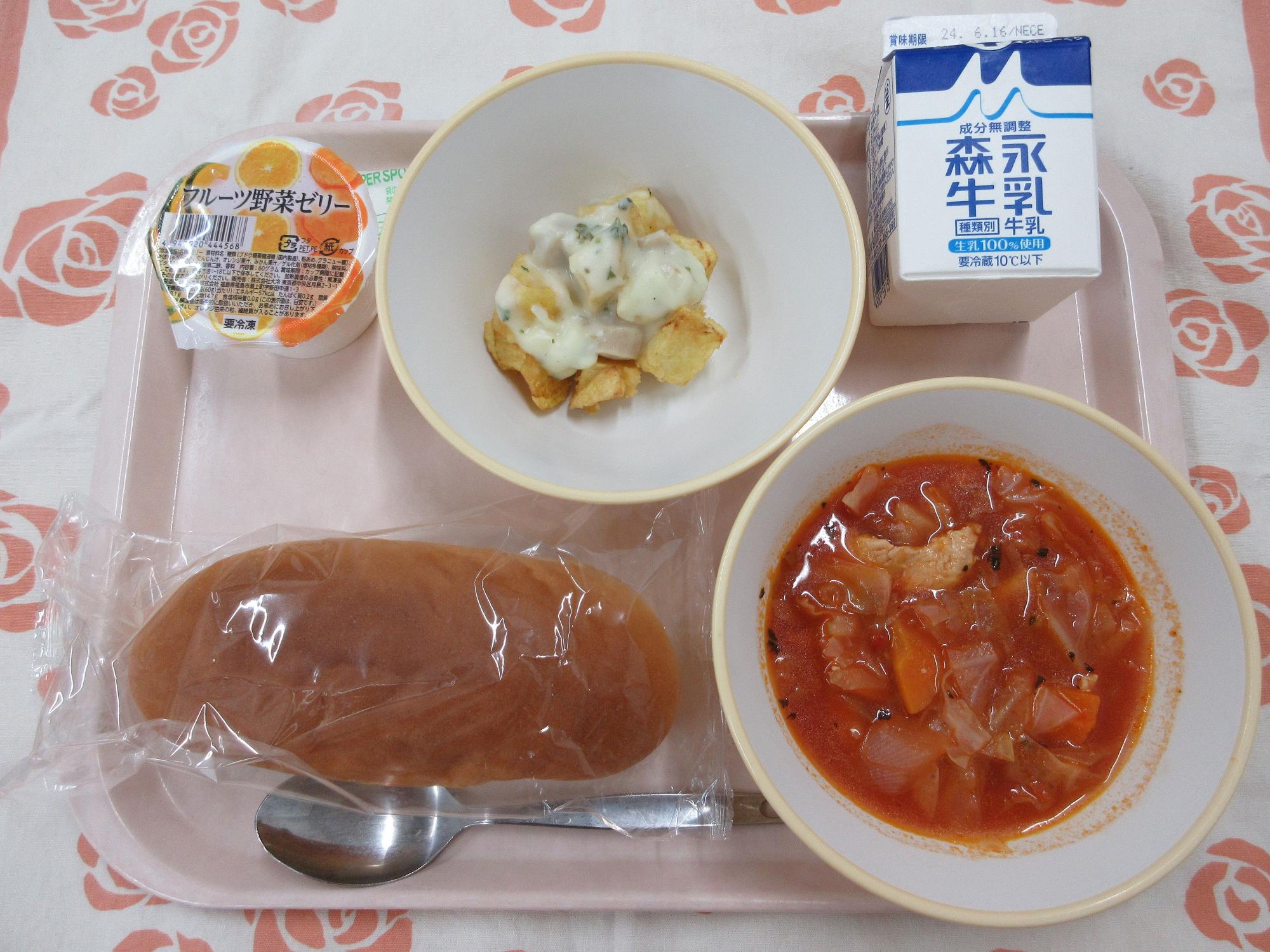 ピンクのトレーに給食が右上から反時計回りで牛乳、ポテトのチーズソース、フルーツ野菜ゼリー、コッペパン、トマトスープと並んでいる写真