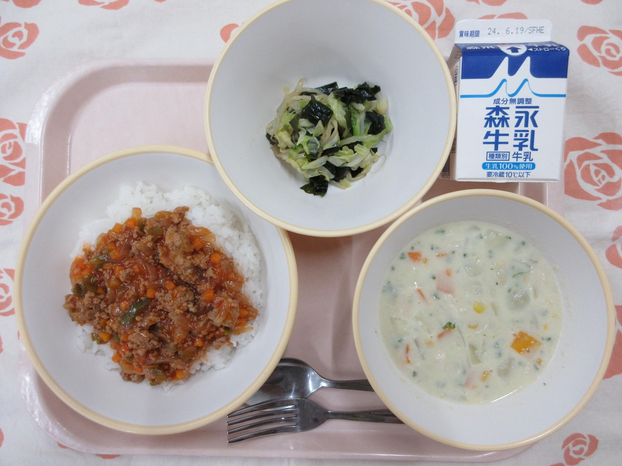 ピンクのトレーに給食が右上から反時計回りで牛乳、海藻サラダ、タコライス、コーンのミルクスープ と並んでいる写真