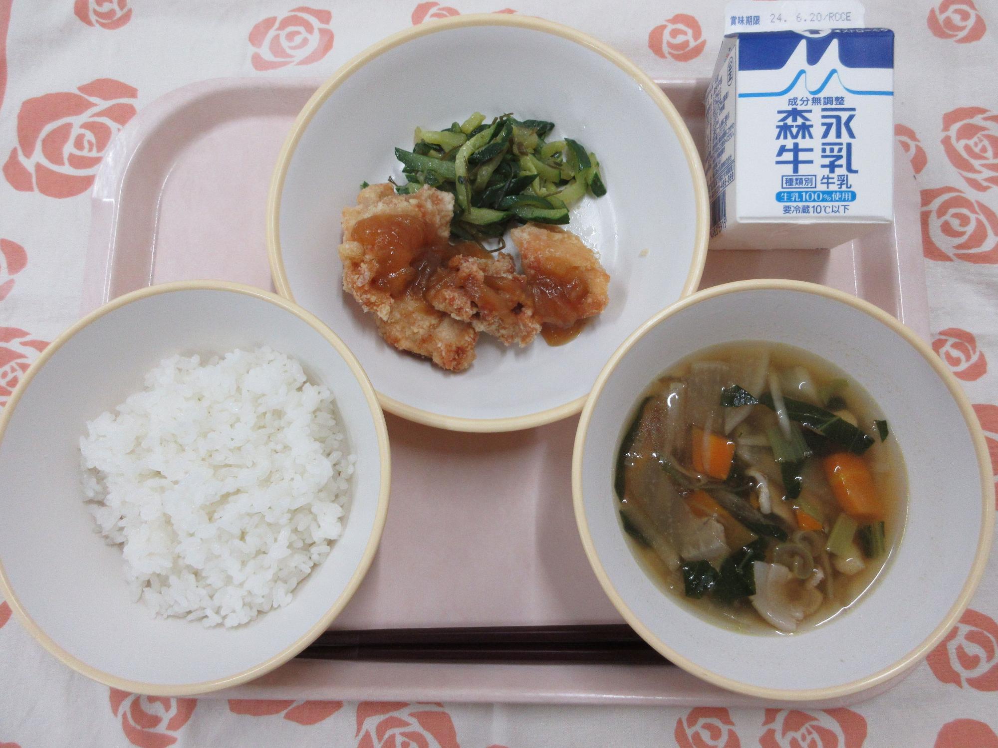 ピンクのトレーに給食が右上から反時計回りで牛乳、鶏肉のバーベキューソースとピリ辛きゅうり、ご飯、根菜汁と並んでいる写真