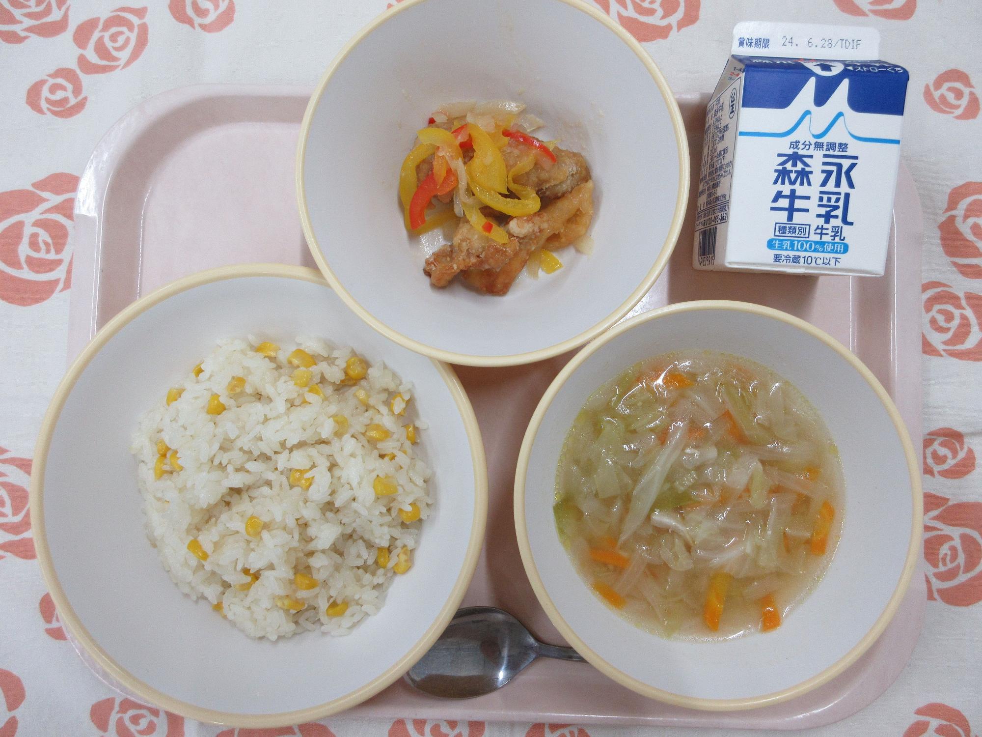 ピンクのトレーに給食が右上から反時計回りで牛乳、鶏肉のマリネ、コーンピラフ、コンソメスープと並んでいる写真