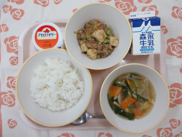 ピンクのトレーに給食が右上から反時計回りで牛乳、肉豆腐あんかけ、アセロラゼリー、ご飯、鶏けんちん汁と並んでいる写真