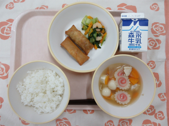 ピンクのトレーに給食が右上から反時計回りで牛乳、春巻きとチンゲンサイの塩炒め、ご飯、白玉スープと並んでいる写真