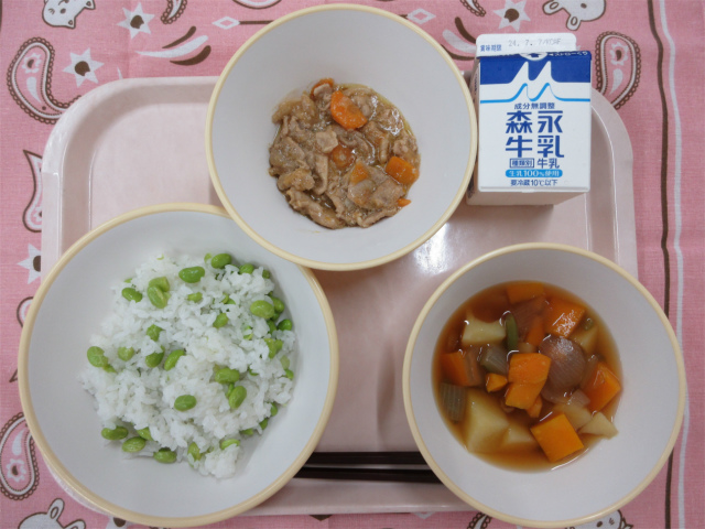 ピンクのトレーに給食が右上から反時計回りで牛乳、豚肉のみそ炒め、枝豆おこわ、野菜の旨煮と並んでいる写真