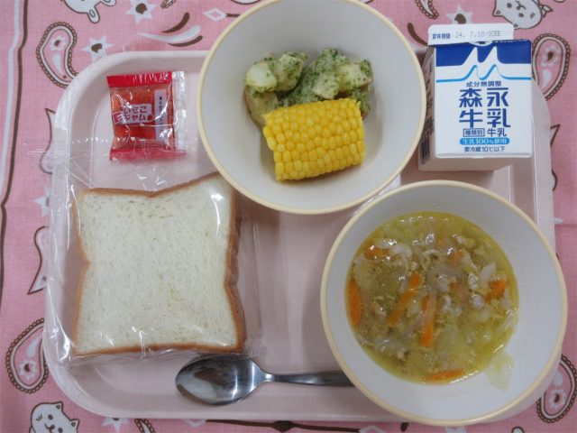 ピンクのトレーに給食が右上から反時計回りで牛乳、とうもろこしと青のりポテト、ちごジャム、食パン、スコッチブロスと並んでいる写真