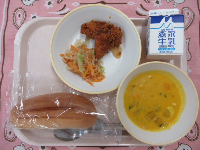 ピンクのトレーに給食が右上から反時計回りで牛乳、チキンカツ とツナサラダ、コッペパン、かぼちゃのクリームスープと並んでいる写真