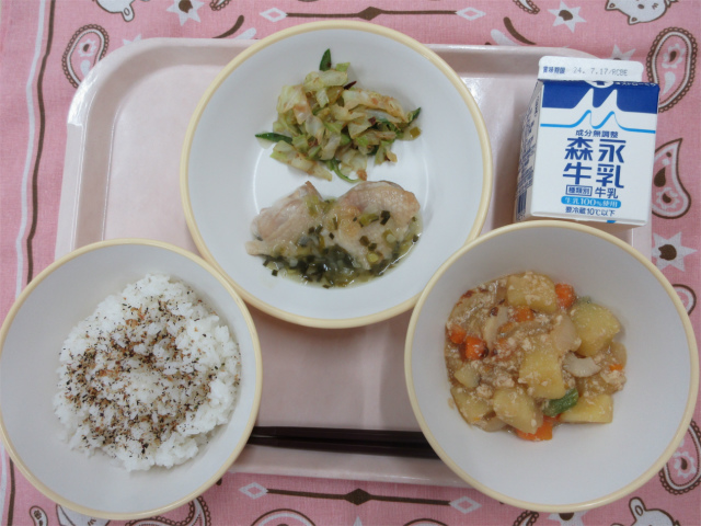 ピンクのトレーに給食が右上から反時計回りで牛乳、鶏肉のねぎ塩焼きとキャベツのおかか和え、しそかつおふりかけのごはん、じゃがいものそぼろ煮と並んでいる写真