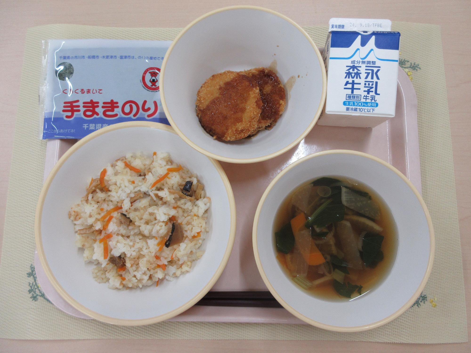 ピンクのトレーに給食が右上から反時計回りで牛乳、キャベツメンチカツ、手巻き海苔、ちらし寿司、けんちん汁と並べられている写真