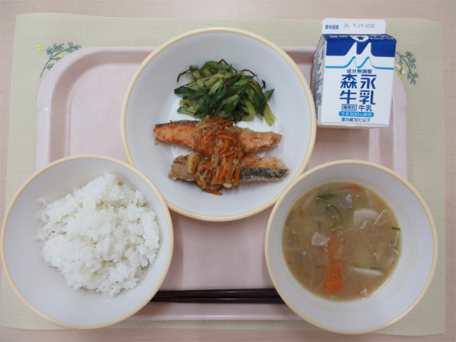 ピンクのトレーに給食が右上から反時計回りで牛乳、ピリ辛きゅうり、鮭のから揚げ野菜あんかけ、ごはん、豚汁と並べられている写真